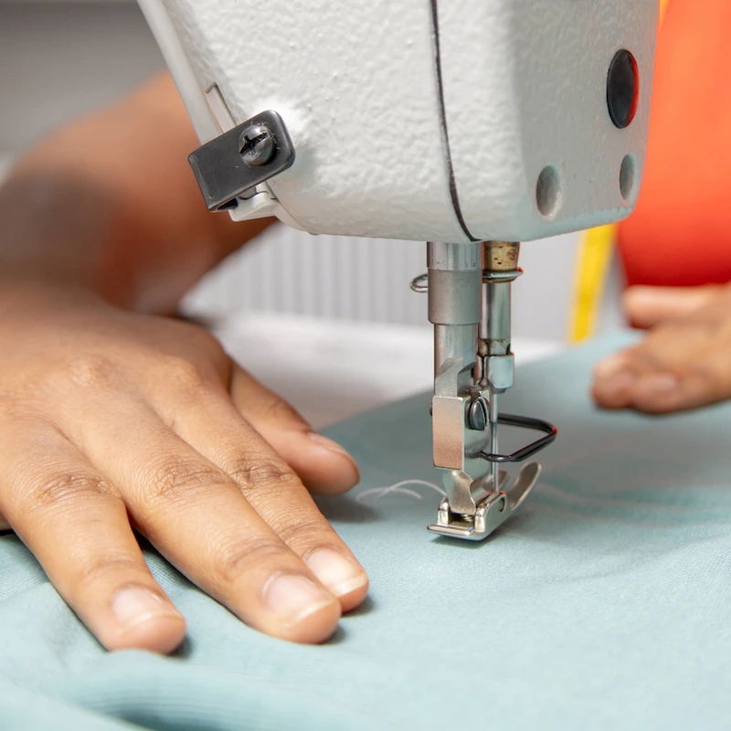 Woman's hands guiding fabric through a sewing machine